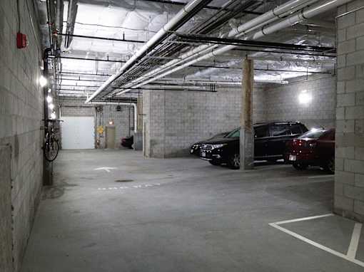 Underground parking garage with concrete pillars and vehicles at 68 Beale Apartments, Quincy, Massachusetts